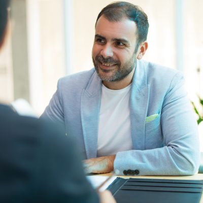 Portrait of smiling mid adult businessman sitting in office. Portrait of Latin American client or customer at bank, lawyer or insurance office. Partnership concept